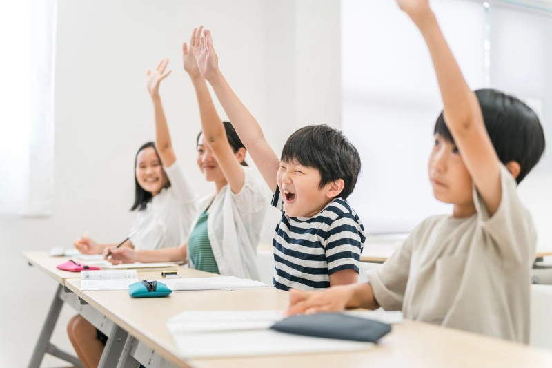 授業中に元気に挙手する小学生の男女生徒